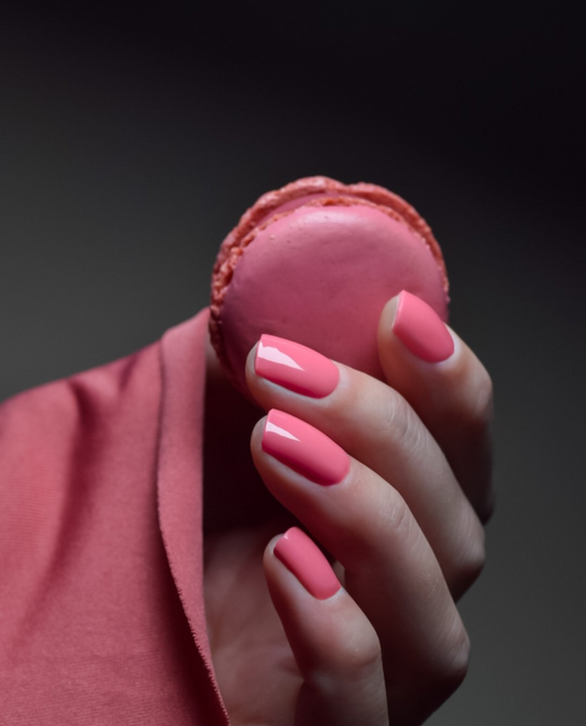 Hand mit UV Gel Wraps Peachy Pink – knallige pinke Nägel mit glänzendem Finish.