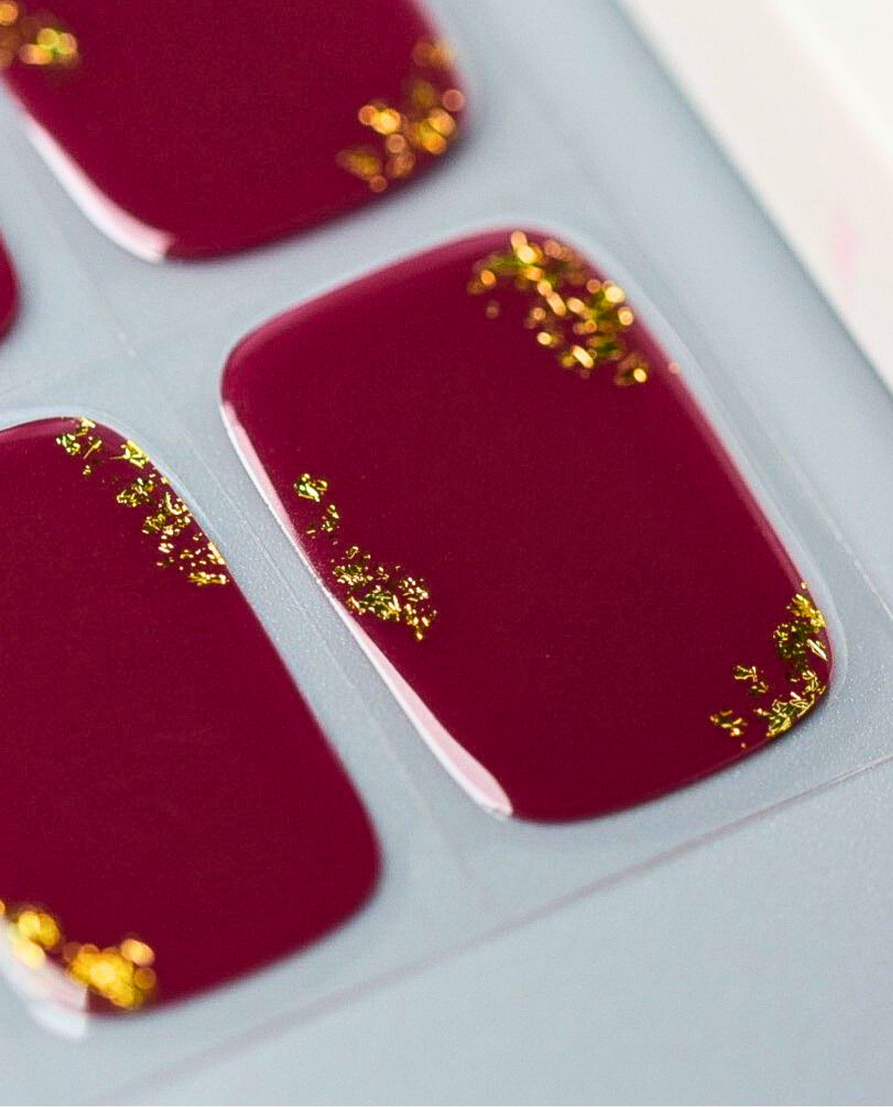 Nahaufnahme Royal Rouge – rote Maniküre mit goldenem Glitzer.