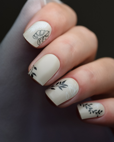 Hand mit UV Gel Wraps Blattgeflüster – Beige Nails mit schwarzen & weißen Blattmustern.