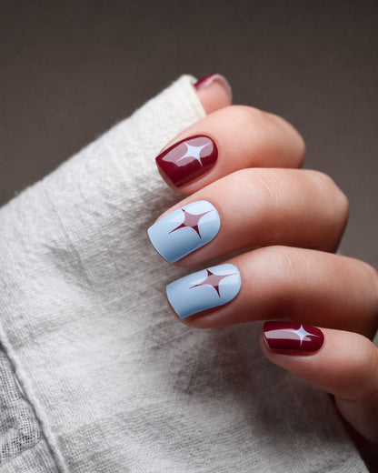 Cherry Cola UV Gel Wraps mit kirschroten und himmelblauen Designs sowie Sternakzenten auf den Fingernägeln.