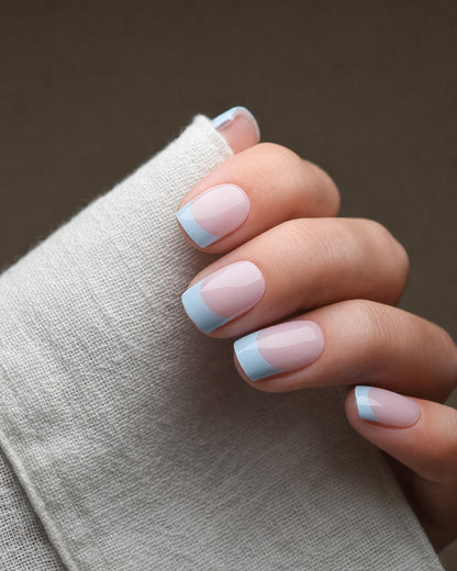 Cloud Nine UV Gel Wraps in zartem Himmelblau und Milchweiß auf den Fingernägeln.