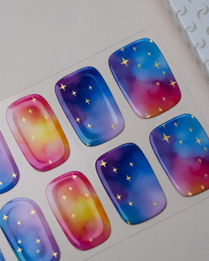 Detailaufnahme der Cotton Candy Cosmos Nailpolish Wraps mit Farbverläufen in Blau, Pink und Violett sowie goldenen Metallic-Sternen.