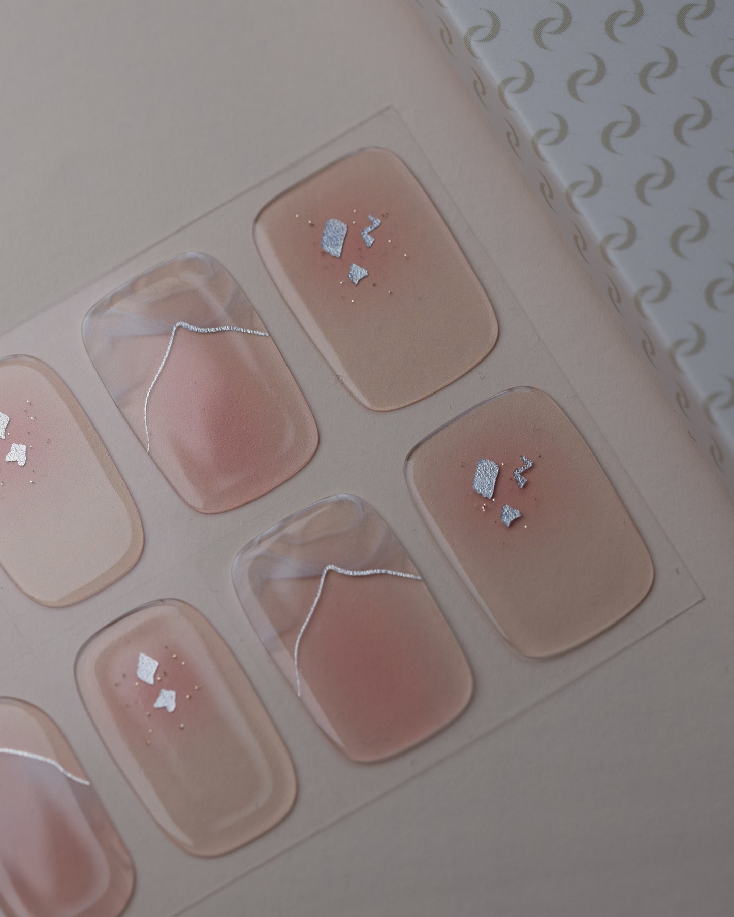 Dusty Glam UV Gel Wraps auf dem Designbogen mit rosafarbenen Nude-Tönen, Schimmer und Glitzerdetails.