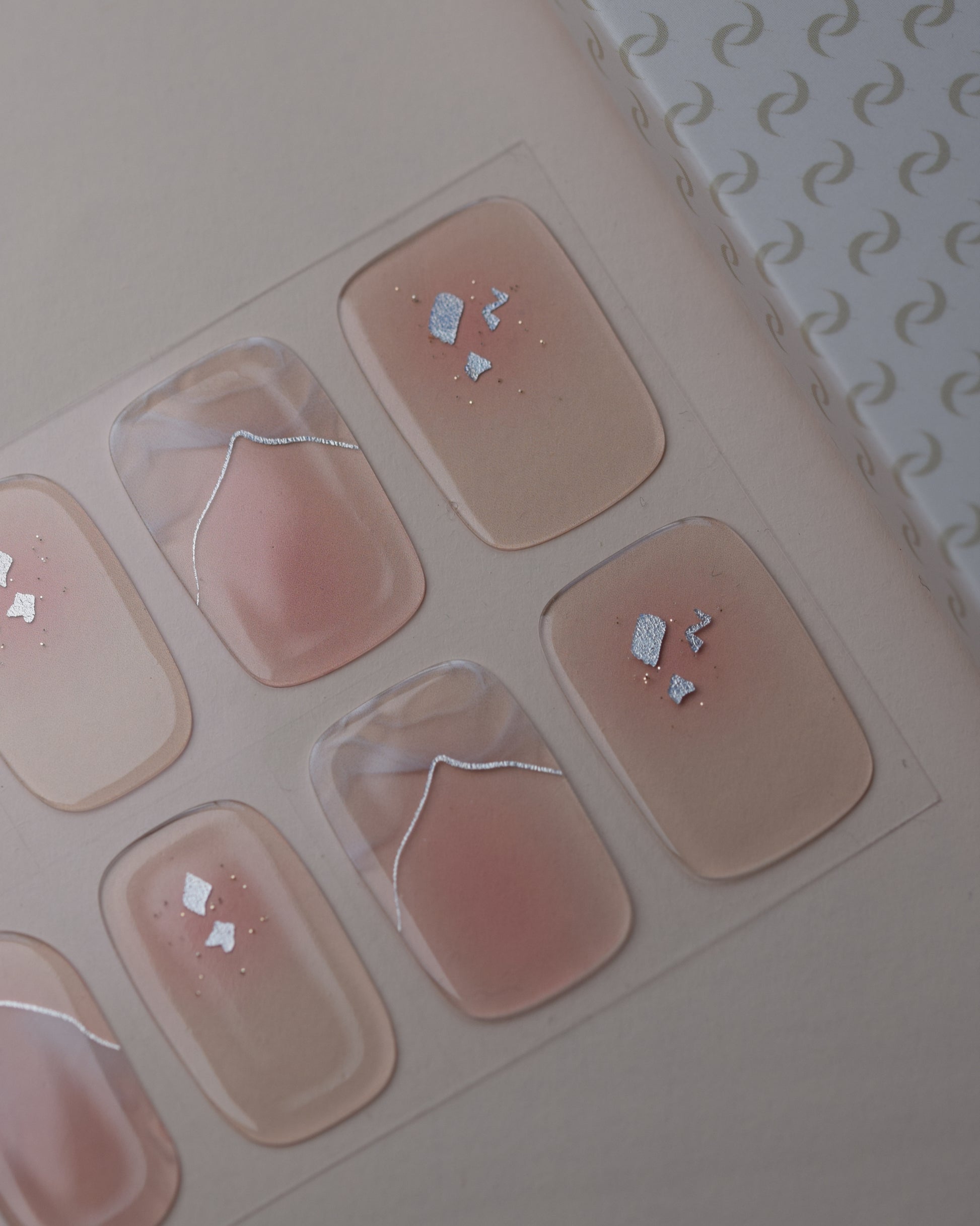 Dusty Glam UV Gel Wraps auf dem Designbogen mit rosafarbenen Nude-Tönen, Schimmer und Glitzerdetails.