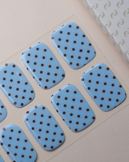Forget Me Dot UV Gel Wraps auf dem Designbogen mit himmelblauem Hintergrund und schwarzem Polka-Dot-Muster.