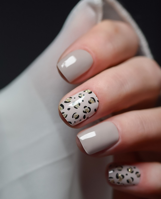 Wild & Fierce – UV Gel Wraps in Nude-Grau mit Leo-Print in Schwarz und Gold aufgetragen.