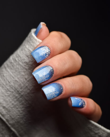 Flockentanz UV Gel Wraps – blaues Winterdesign mit weißen Schneeflocken und sanftem Glanz.