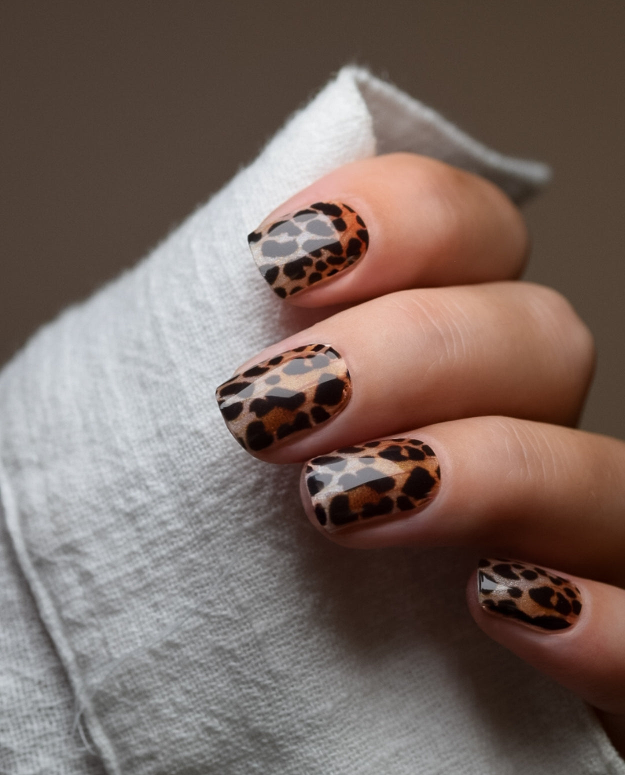 Hand mit UV Gel Wraps Rawr – Nägel im Leo Animal Print Design.