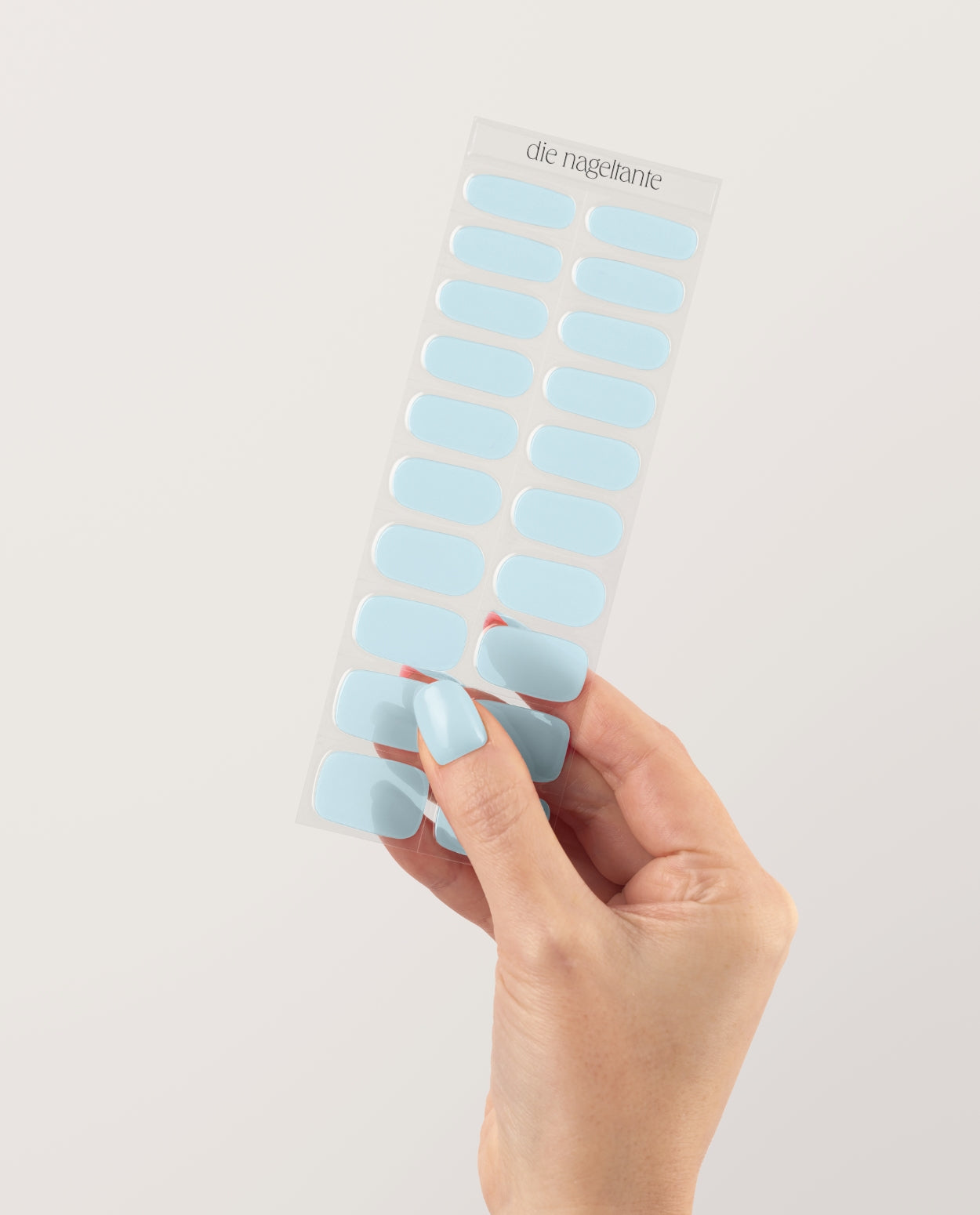 Hand mit UV Gel Wraps im Design Nebelblau – zarte hellblaue Nägel in glänzendem Finish, fotografiert in Nahaufnahme.