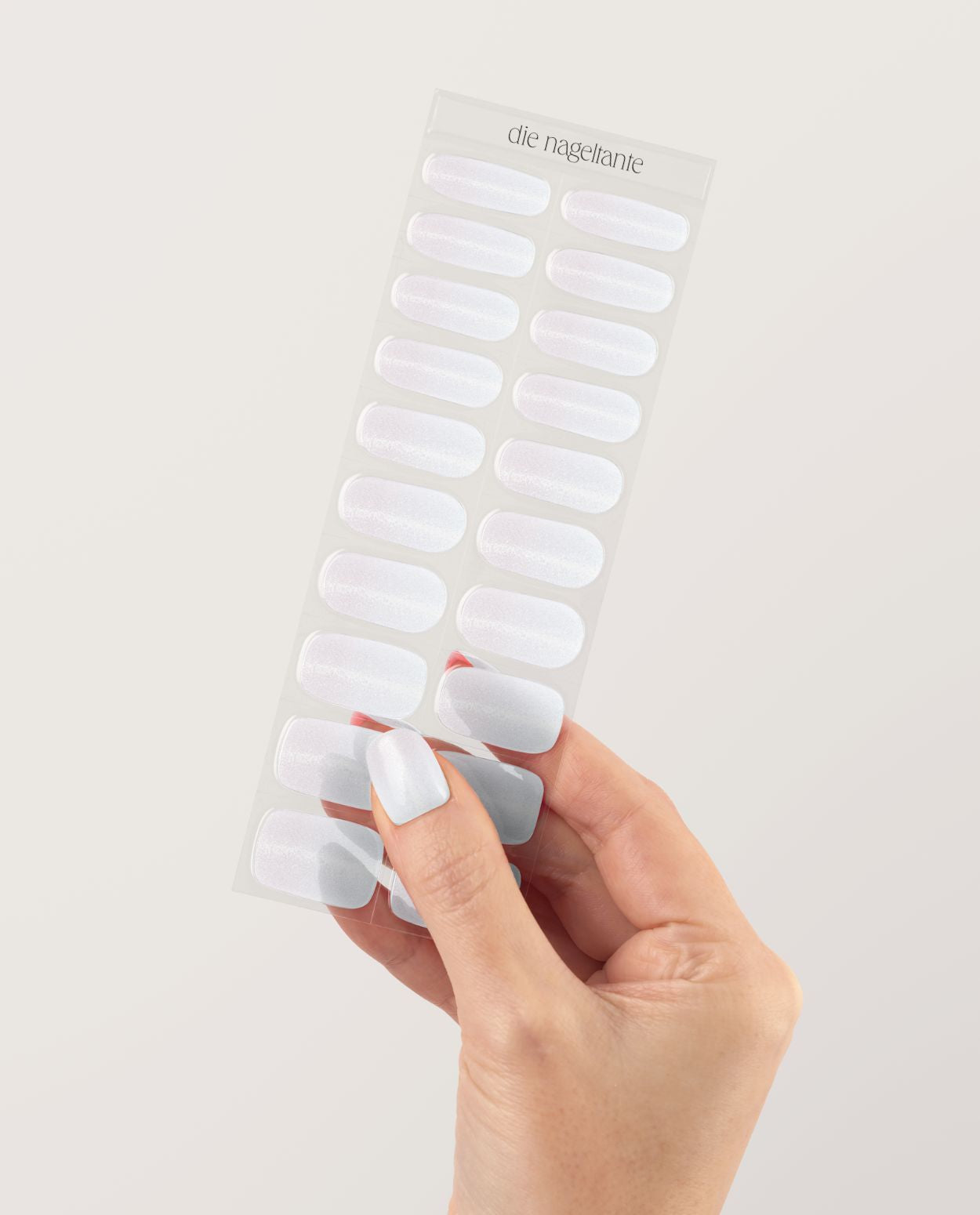 UV Gel Wraps Babyboomer Glimmer – Ombré Nailwraps mit Glanz und Glitzer veredelt - Hand hält Träger der Nail Wraps