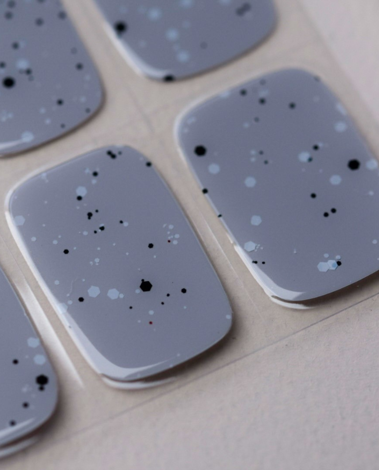 Nahaufnahme Graphite Dust – graue Nägel mit Sprenkel-Details.