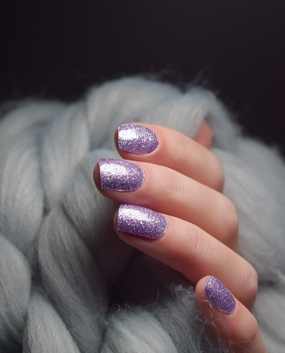 Hand mit UV Gel Wraps Lavender Dust – lavendelfarbene Nägel mit Glitzer-Finish.