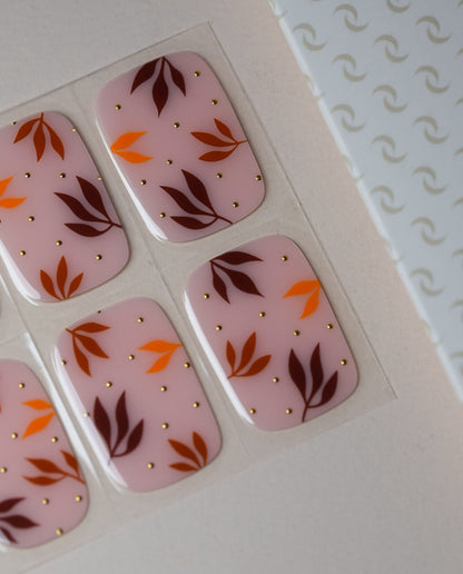 UV Gel Wraps Cinnamon & Gold – Bogen mit semi-cured Streifen in Rosé mit braunen und goldenen Blattmustern.