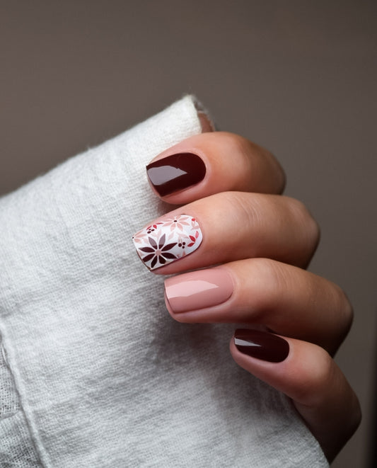 Hand mit UV Gel Wraps Wine Garden – Bordeauxrote Nägel mit floralem Akzentdesign.