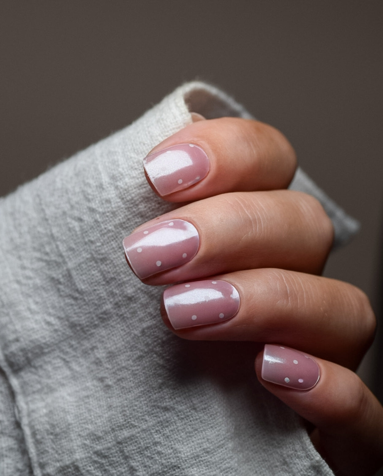 Hand mit UV Gel Wraps Blush & Dots – zarte Rosé-Nägel mit weißen Punkten.