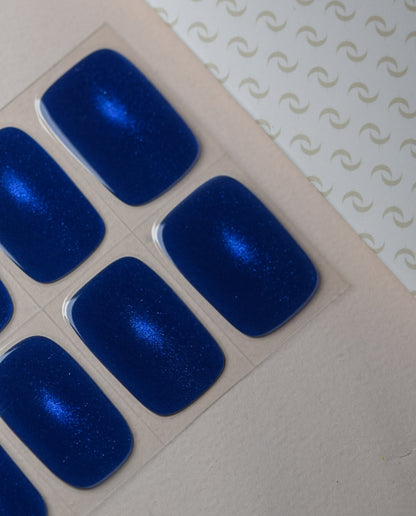 Midnight Tale UV Gel Wraps – tiefblauer Cat Eye Effekt mit galaktischem Glitzerschimmer auf den Nägeln.