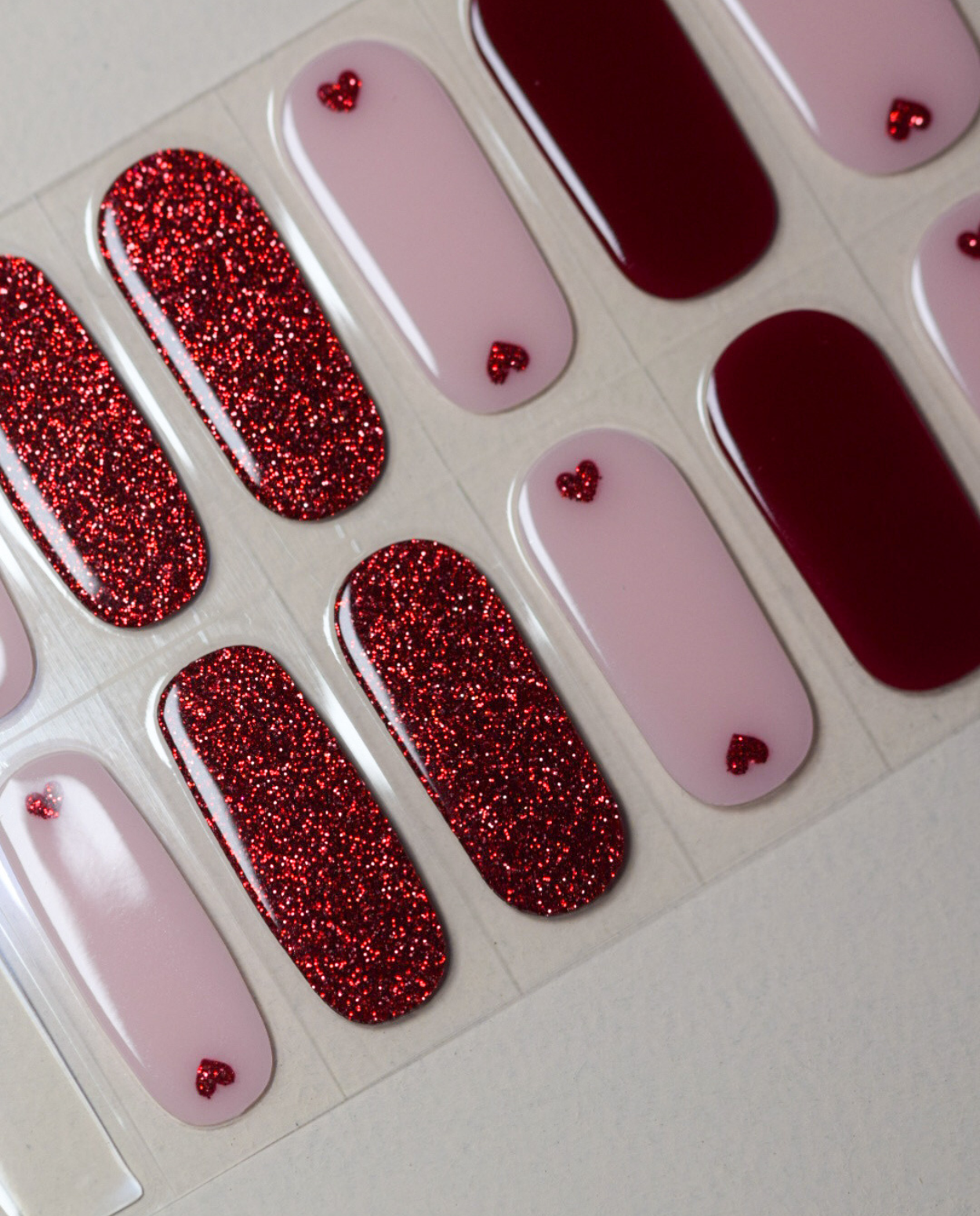 UV Gel Wraps „Little Love Story“ mit roten Glitzerdesigns und zarten Nude-Tönen, Detailansicht