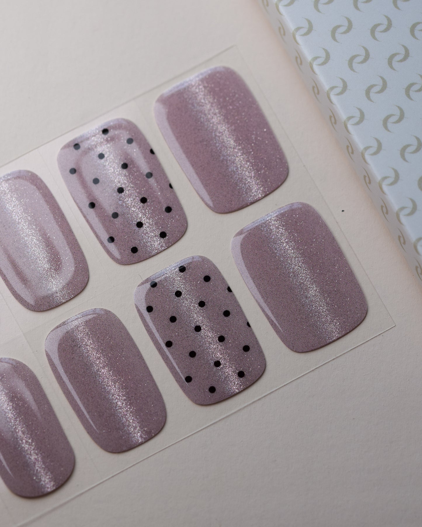Pink Prosecco Cat Eye UV Gel Wraps auf dem Designbogen mit roséfarbenem Cat-Eye-Effekt und schwarzen Akzenten.