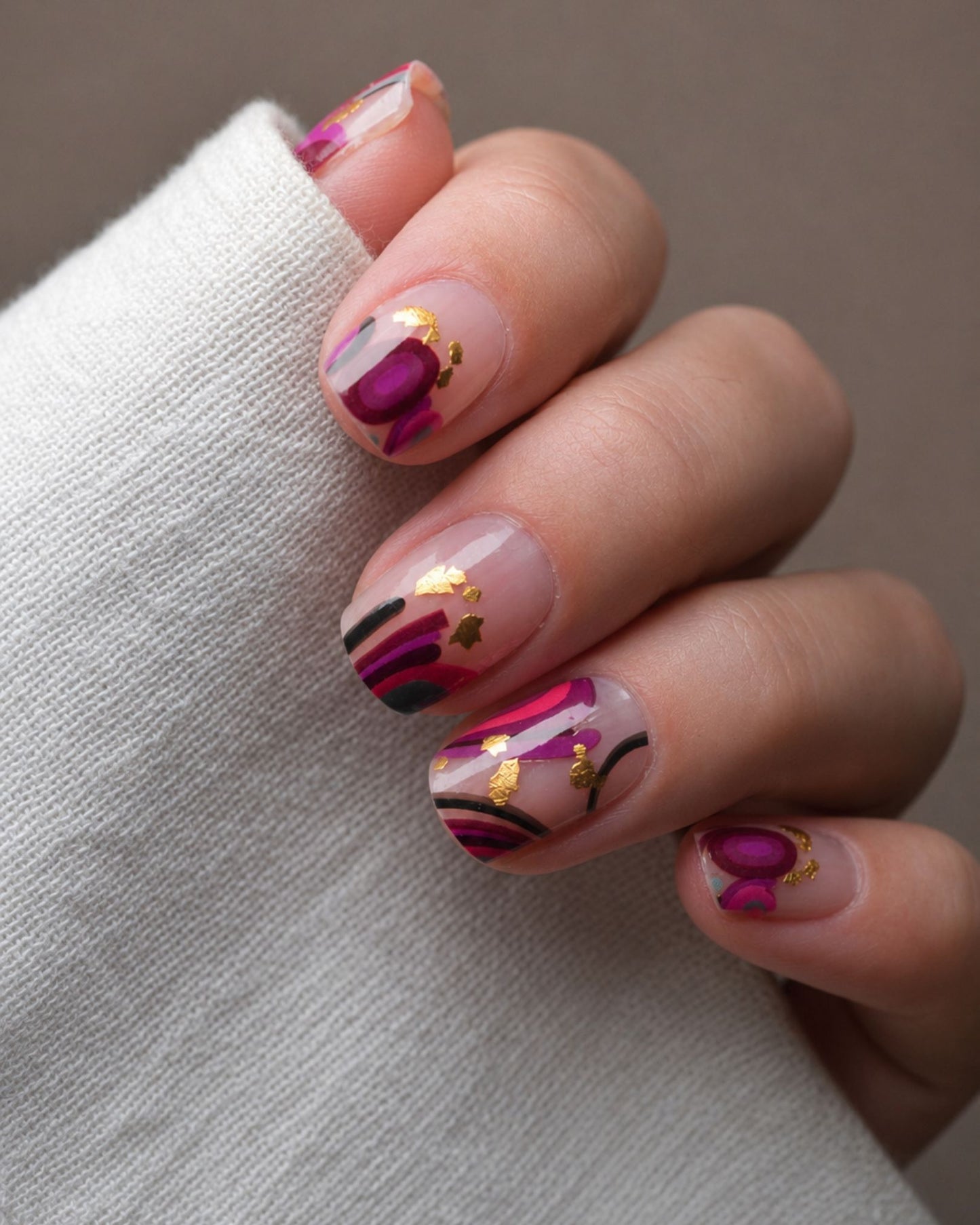 Pinkasso Nailpolish Wraps auf den Fingern getragen – transparentes Design mit abstrakten Formen und goldenen Flakes.