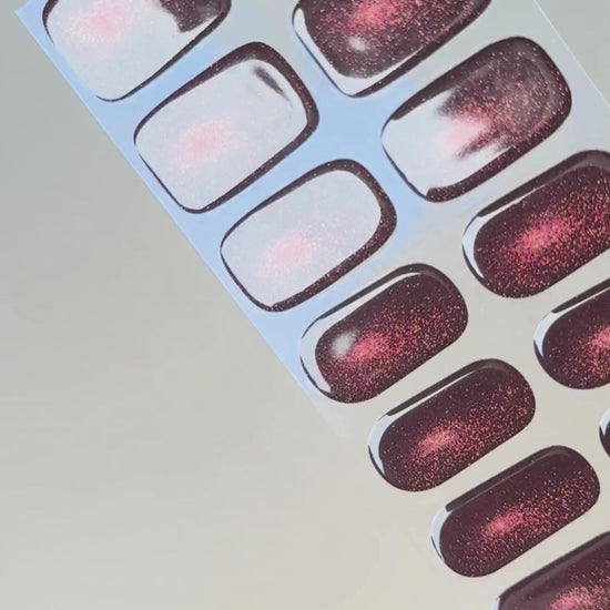 Anwendung und Detailansicht der Burning Ruby Cat Eye UV Gel Wraps mit rubinrotem Cat-Eye-Effekt und funkelndem Schimmer.