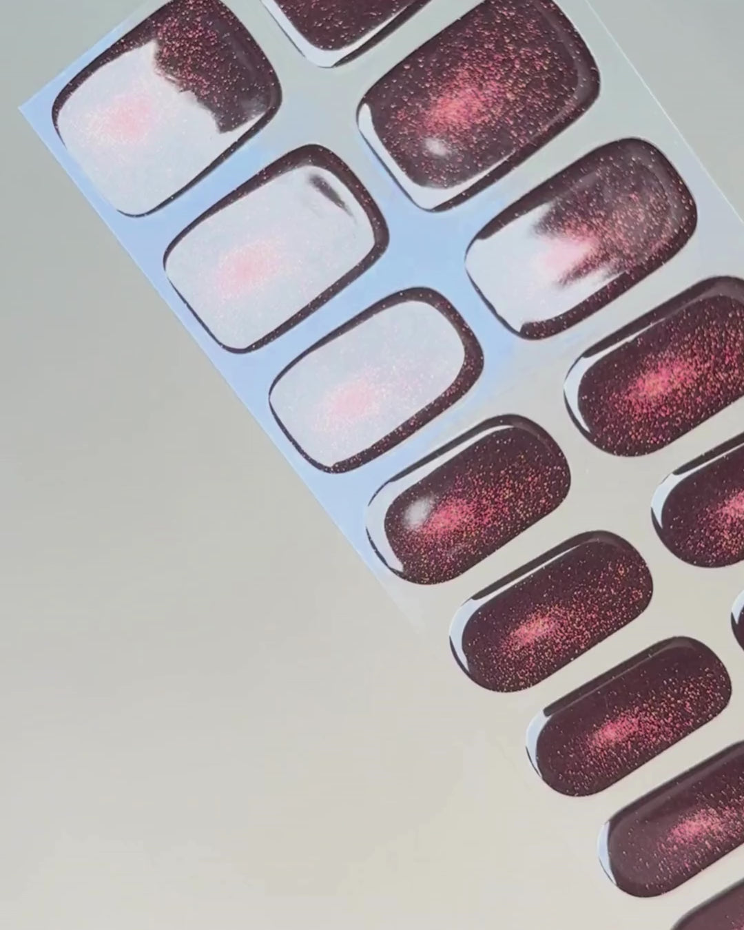Anwendung und Detailansicht der Burning Ruby Cat Eye UV Gel Wraps mit rubinrotem Cat-Eye-Effekt und funkelndem Schimmer.