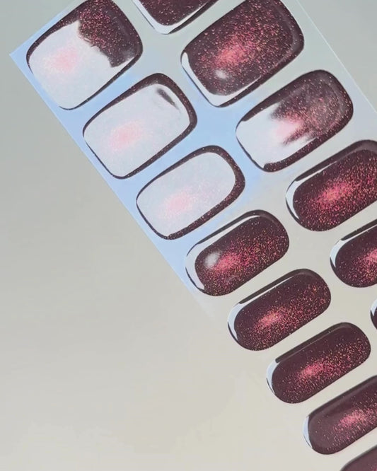 Anwendung und Detailansicht der Burning Ruby Cat Eye UV Gel Wraps mit rubinrotem Cat-Eye-Effekt und funkelndem Schimmer.