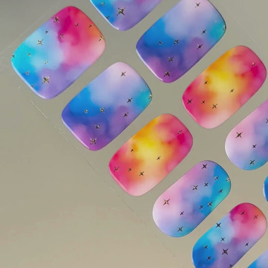 Anwendung und Detailansicht der Cotton Candy Cosmos Nailpolish Wraps mit leuchtenden Galaxie-Farben und goldenen Metallic-Sternen.