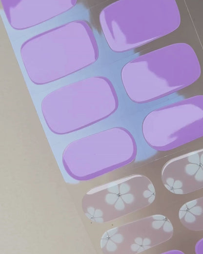 Video zur Anwendung und Ergebnis der Bloom, Please UV Gel Wraps mit lilafarbenem Design und Blüten-Details. Schritt für Schritt Aufkleben und Aushärten für eine langanhaltende Maniküre mit uv nailwraps von Die Nageltante.