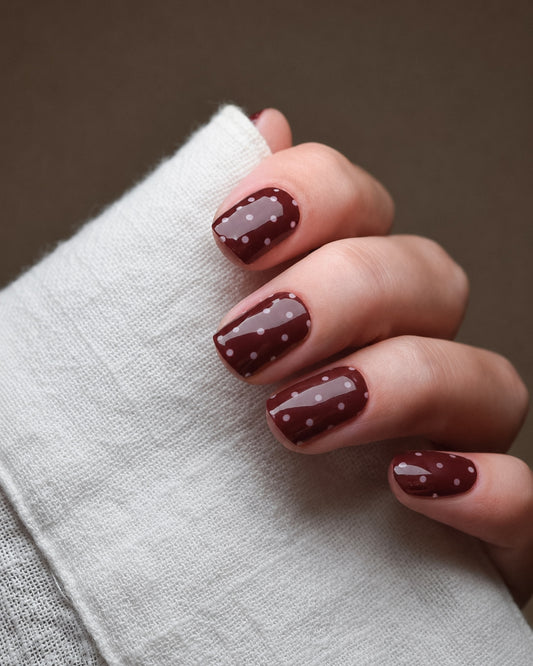 Ruby Dots UV Gel Wraps in tiefem Rubinrot mit weißen Punkten auf den Fingernägeln.