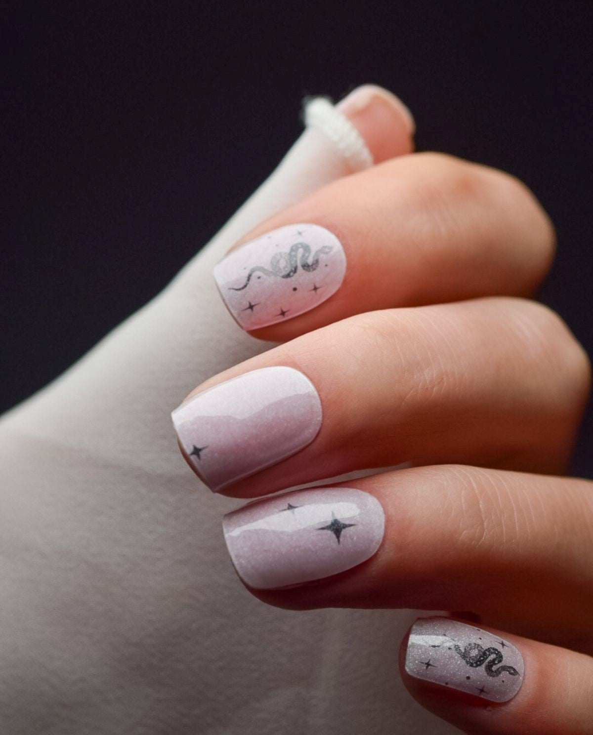 Maniküre mit UV Gel Wraps Starbite – weißes Design mit silbernen Sternen und Snake-Details